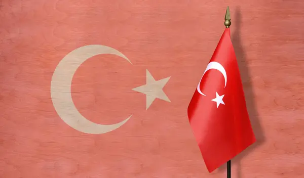 Tabletop flag of Turkey against a background of a pale image of the flag