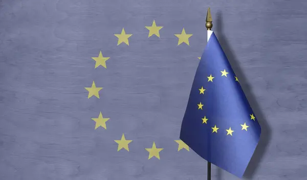 A small EU flag against a background of a pale image of the EU flag