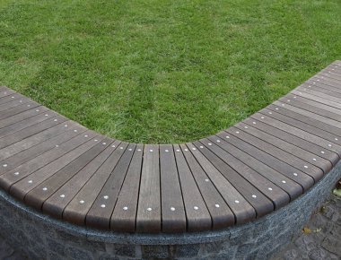 Düz ahşap bloklardan oluşan eğri bir sıra şeklinde bir park bankı..