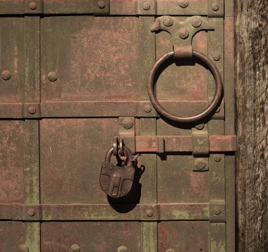 Eski işlenmiş demir kapı. Sürgülü, asma kilitli ve metal halkalı.