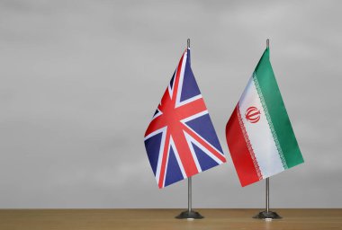 Gri arkaplanda Birleşik Krallık ve İran bayrakları