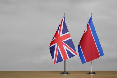 Gri arka planda Birleşik Krallık ve Kuzey Kore bayrakları