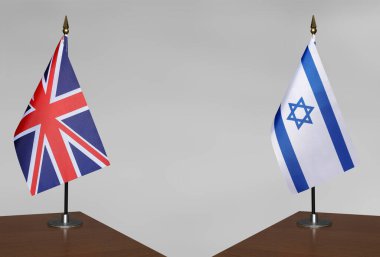 Birleşik Krallık ve İsrail 'in bayrakları gri bir arka planda duruyor
