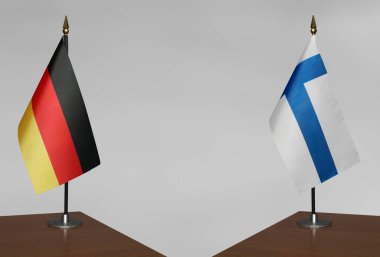 Almanya ve Finlandiya 'nın bayrakları gri arka planda duruyor