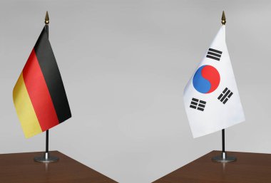Almanya ve Güney Kore 'nin bayrakları gri arka planda duruyor