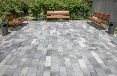 Düz fayanslı bir alan ve üç bank. Şehir parkında dinlenmek için bir yer.