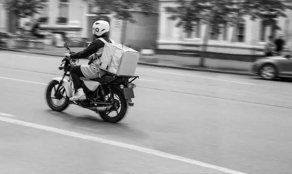 Motosikletli bir kurye mal teslimatı siparişini yerine getirir. Bulanık arkaplan.