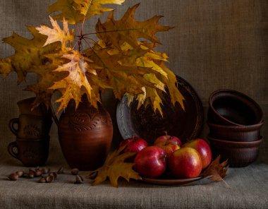 Kırmızı elmalar, kuru meşe yaprakları ve seramik tabaklarla sonbahar kompozisyonu