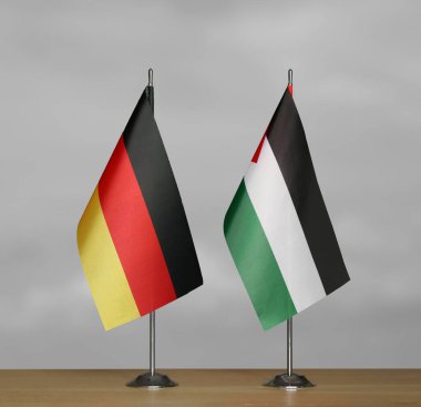 Almanya ve Filistin 'in masa üstü bayrakları gri bir arka planda duruyor