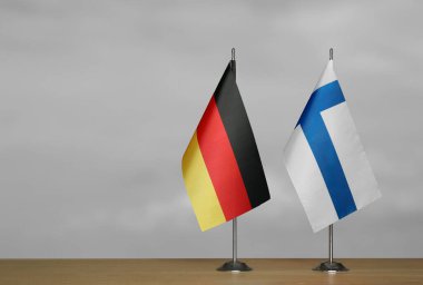 Almanya ve Finlandiya 'nın bayrakları gri arka planda duruyor