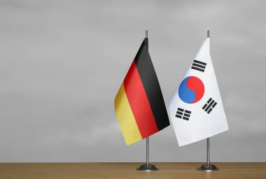 Almanya ve Güney Kore 'nin bayrakları gri arka planda duruyor