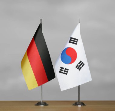 Almanya ve Güney Kore 'nin bayrakları gri arka planda duruyor