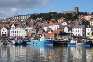 Scarborough, Kuzey Yorkshire, İngiltere - 12 Eylül 2022: Limanda demirlemiş balıkçı tekneleriyle birlikte yazın Scarborough kasabasının manzarası