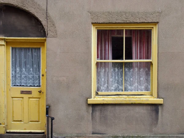 黄色の塗装されたドアと窓のある典型的な古い小さな英語のテラスハウスの正面図 — ストック写真