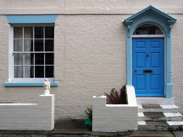 stock image front view of a typical old small english terraced brick house white painted wall and blue door