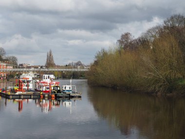 Chester mı? Cheshire, Birleşik Krallık - 20 Mart 2024: Chester 'daki Dee nehrinin nehir kıyısına demirlemiş tekneleri ve Queens Park asma köprüsü manzarası