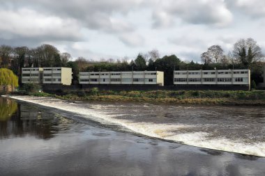 the weir on the river Dee in Chester with apartments on the far bank clipart