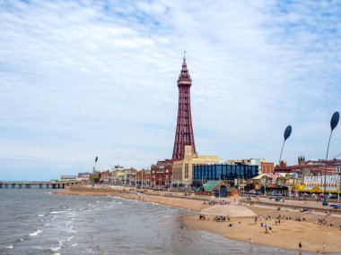 Blackpool, Lancashire, Birleşik Krallık - 27 Temmuz 2024: Blackpool 'da deniz kenarındaki kulede deniz kenarındaki binalar ve yazları plajdaki insanlar
