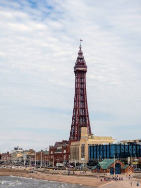 Blackpool, Lancashire, Birleşik Krallık - 26 Haziran 2024: Gezinti alanı boyunca binalar ve deniz kenarındaki insanlarla çevrili Blackpool kulesi