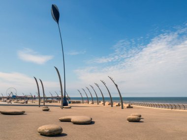 Blackpool 'daki gezinti güvertesinde arka planda merkez iskele ve mavi bir yaz denizi manzarası.