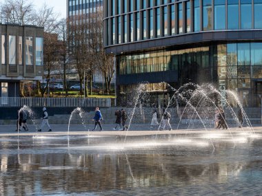 Bradford, Batı Yorkshire, Birleşik Krallık - 18 Mart 2025: Bradford Centenary Meydanı 'ndaki fıskiyelerin yanından geçen insanlar