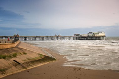 Alacakaranlıkta Blackpool 'un kuzey rıhtımının manzarası. Gün batımı gökyüzü ve kumsalda dalgalar var.