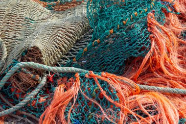 Parlak yeşil ve turuncu renklerde birbirine dolanmış ticari balıkçı teknesi ağları.