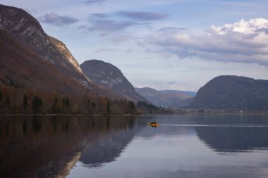 Önplanda bir kanoyla Bohinj Gölü 'nde sonbahar yansımaları.