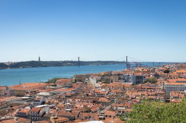 Arka planda Ponte 25 de Abril Köprüsü ve Santuario de Cristo Rei 'nin bulunduğu çatılar, Lizbon, Portekiz' de yer alıyor.