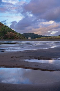 Güzel Bethells sörf plajında yansıtıcı gün batımı anı, Auckland, Yeni Zelanda
