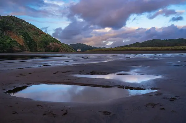 Beautiful sunset ponds reflections at the Bethells surf beach, Auckland, New Zealand
