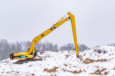 Polonya, Biedrusko - 23.01. 2023. Karla kaplı sarı bir kumun üzerinde duran bir kazıcı.