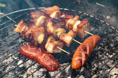 Ev portatif ızgarada ızgara sosis, pastırma ve soğan.