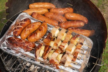 Ev portatif ızgarada ızgara sosis, pastırma ve soğan.