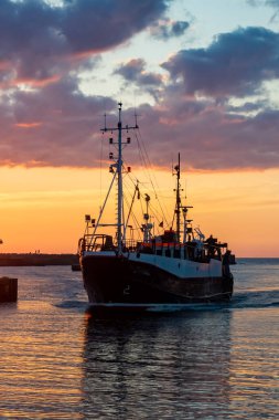 Gün batımında Ustka limanına giren bir gemi.