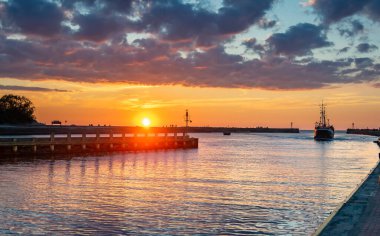 Gün batımında Ustka limanına giren bir gemi.