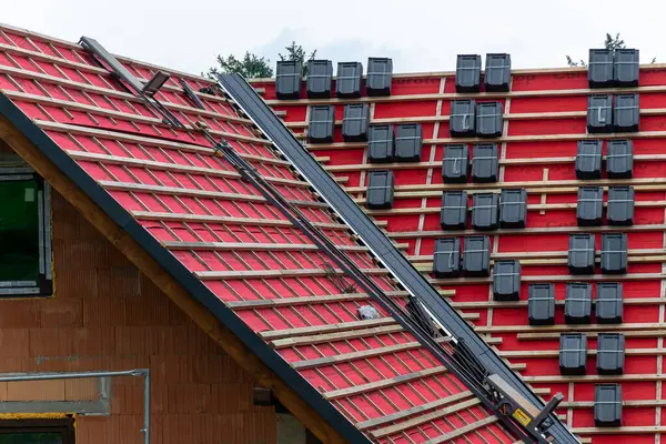 stock image Karpacz, Poland - August 08, 2024 - laying roof tiles on a roof covered with red membrane