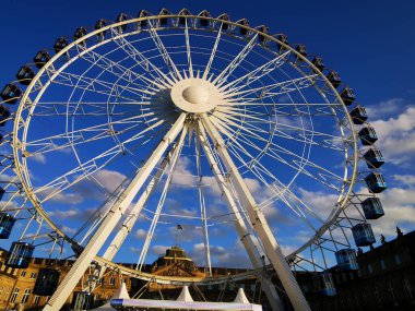Dönme dolap, Stuttgart 'taki New Palace' ın önündeki avluda. Cazibe kış güneşinde parlıyor. Arka planda muhteşem kalenin merkez binasını görebilirsiniz: bakır çatıda ulusal bayrak dalgalanıyor.