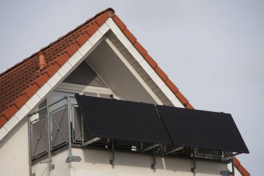 Çatı katının balkonunda balkon güç santrali. Ev enerjik bir şekilde yenilendi ve büyük güneş panelleri balkon korkuluklarının önüne mümkün olduğunca çok güneş ışığını yakalamak için bir açıyla yerleştirildi.