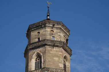 Stuttgart Kolej Kilisesi 'nin batı kulesi. Sekizgen kulenin en üst noktası, balyozdaki filigran duvarcılığını gösteriyor. Kulenin düz çatısı şakacı bir rüzgar horozu tarafından taçlandırıldı.
