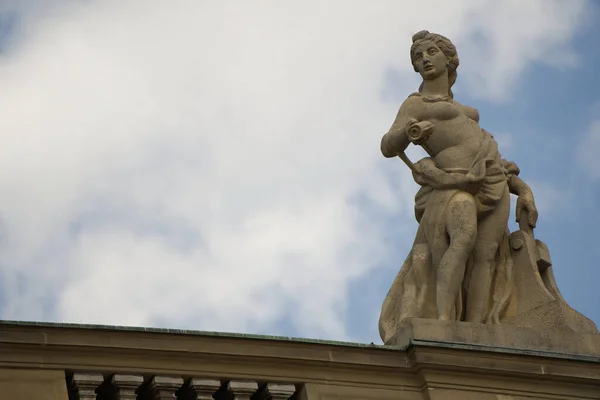 シュトゥットガルトのシュロスプラッツの上にある優雅な彫像は 曇った空に広がっています 右手に巻物を持つ魅力的な女性像は 印刷の芸術を象徴しています 左手は印刷機にある — ストック写真