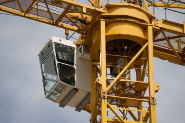 İnşaat alanında görev yapan ağır bir vinç. Manzara vinç operatörünün kulübesine gidiyor.