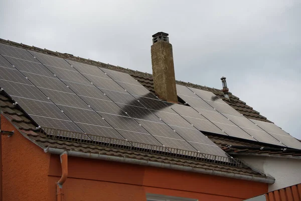 주거용 지붕에 하늘은 대부분 회색이지만 패널에 태양이 비추고 전기가 생산되고 — 스톡 사진