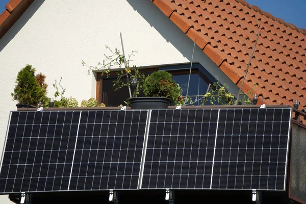 阳台上的发电站在阳光下 栏杆为4个太阳能组件提供了空间 由于阳光明亮 产生了大量的电 阳台上的西红柿也预示着不久会有大丰收 — 图库照片#