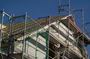 Modern apartman şu anda yapım aşamasında. Yeni bina hâlâ iskele ile çevrili. Çatı zaten fayanslarla kaplı, şimdi ön cephe yalıtılıp sıvanabilir..