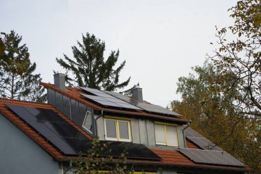 Ağaçlar arasında cennet gibi bir ev. Güneş modülleri çatıya ve yüksek yurt penceresine yerleştirildi. Elektrik gökyüzü gri olsa bile üretilir.