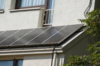 A balcony power plant mounted on a small bay window in full sunshine. A lot of electricity is being produced clipart