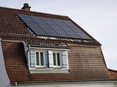 Kar evin çatısındaki güneş panellerinden eridi, ama gri bir kış gününde daha az elektrik üretilir.