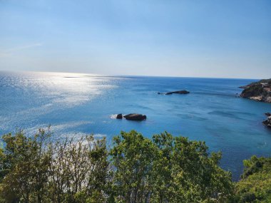 Güneşli bir günde mavi deniz kıyısında kayalar.