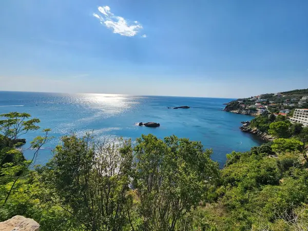 Güneşli bir günde mavi deniz kıyısında kayalar.